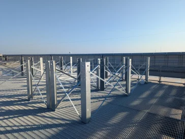 Steel rooftop framing structure under construction with metal grating and cross bracing.