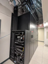 Industrial cooling system with insulated pipes and black equipment unit inside a mechanical room.