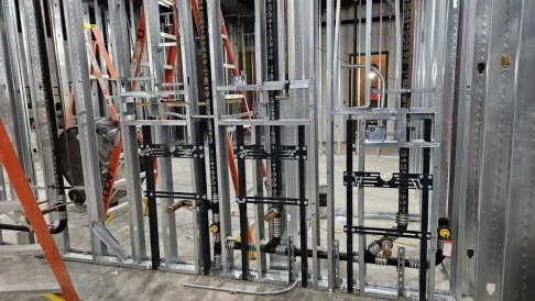Interior commercial construction showing ductwork, piping, and wall framing
