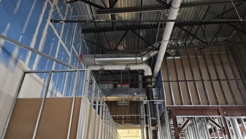 Commercial construction project with exposed piping, steel framing, and mechanical systems